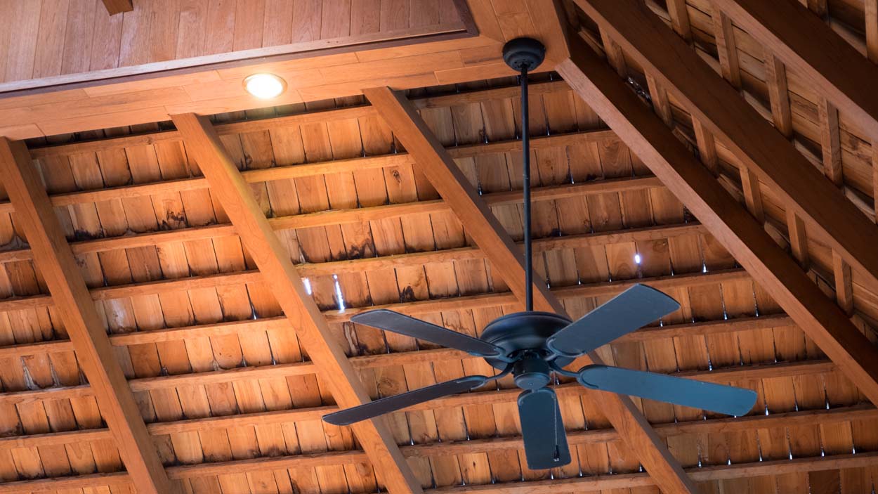 Ceiling fan hanging from wood roof in the room interior